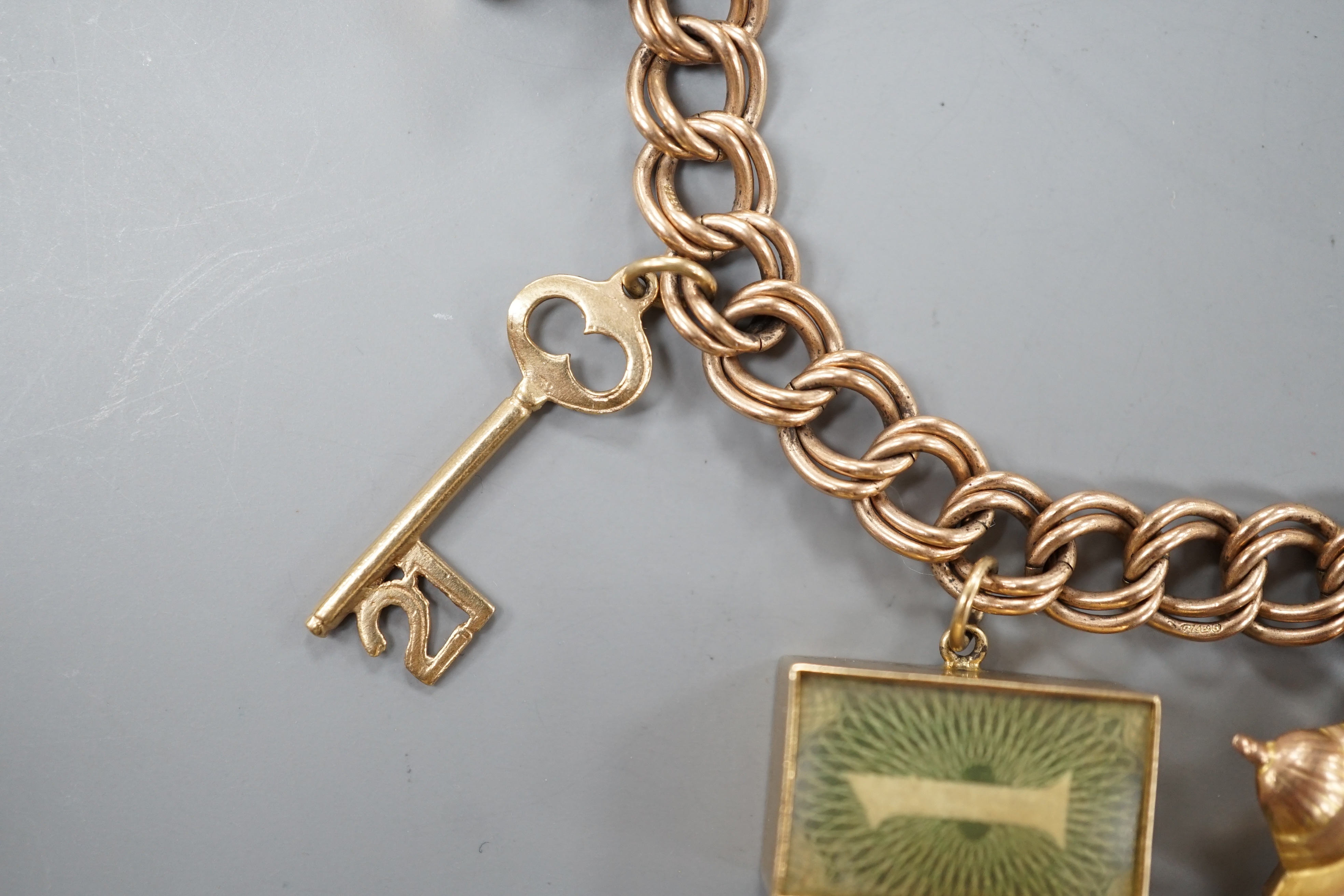 A 1960's 9ct gold charm bracelet, hung with eight assorted mainly 9ct gold charms and a 22ct gold wedding band, gross 28.4 grams.